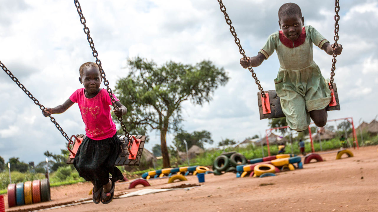 Kinderen spelen op de schommels in kamp Omugo