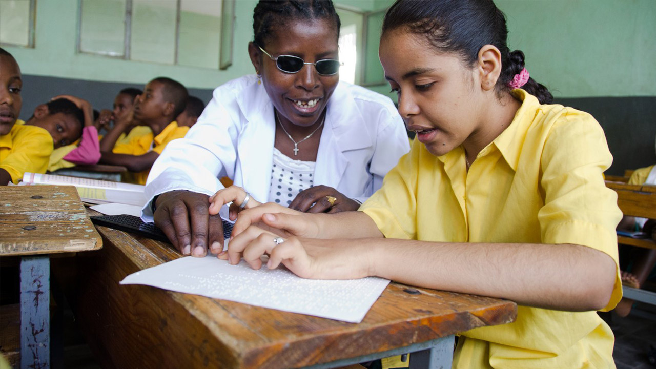 Een blind meisje leert braille in een gewone schoolklas
