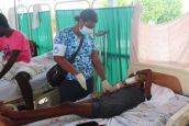 Een kinesitherapeute verleent revalidatiezorg aan een patiënt die gewond raakte bij de aardbeving. Haïti, 2021. 