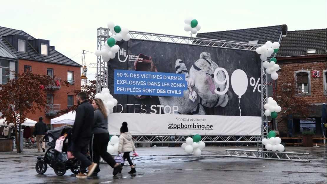 Een koppel met een kindje stapt voorbij een enorme banner 