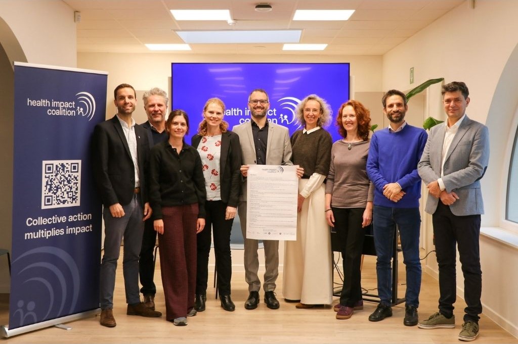 De directeuren van de acht aangesloten ngo's staan met het logo van de coalitie op de achtergrond.