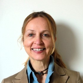 Une femme portant un blazer beige et une chemise bleue.