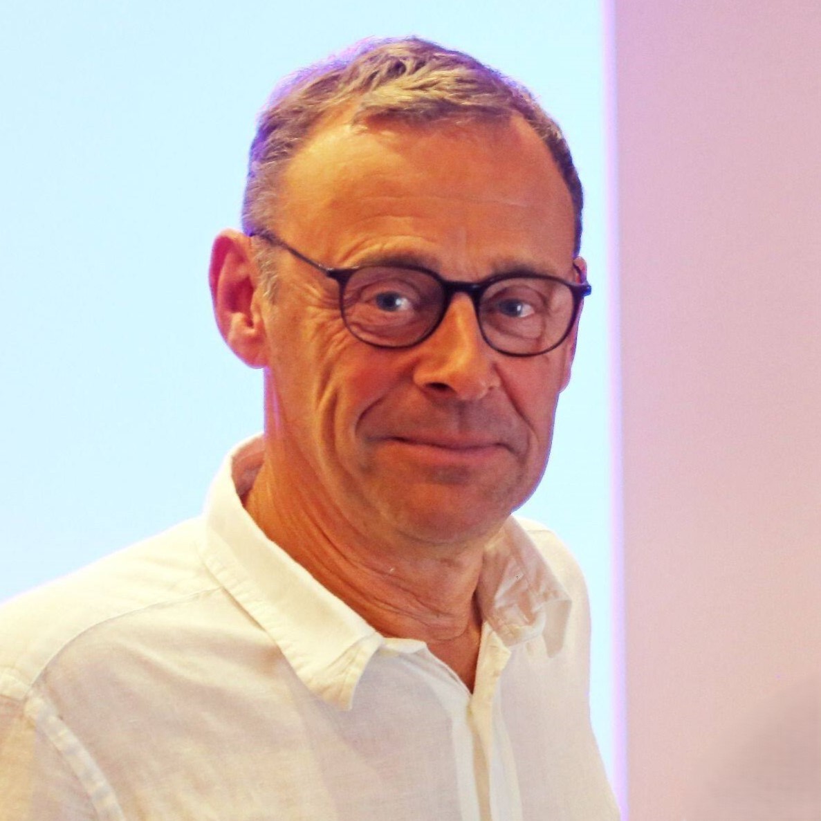Un homme portant des lunettes et une chemise blanche.