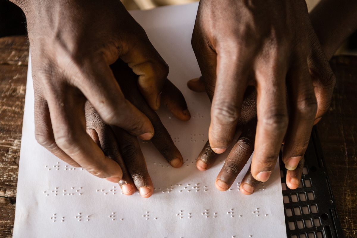 Mains superposées sur un texte écrit en braille.