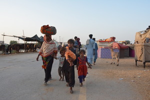 Une famille marche dans un camp pour des personnes déplacées. © Development Tales Media / HI