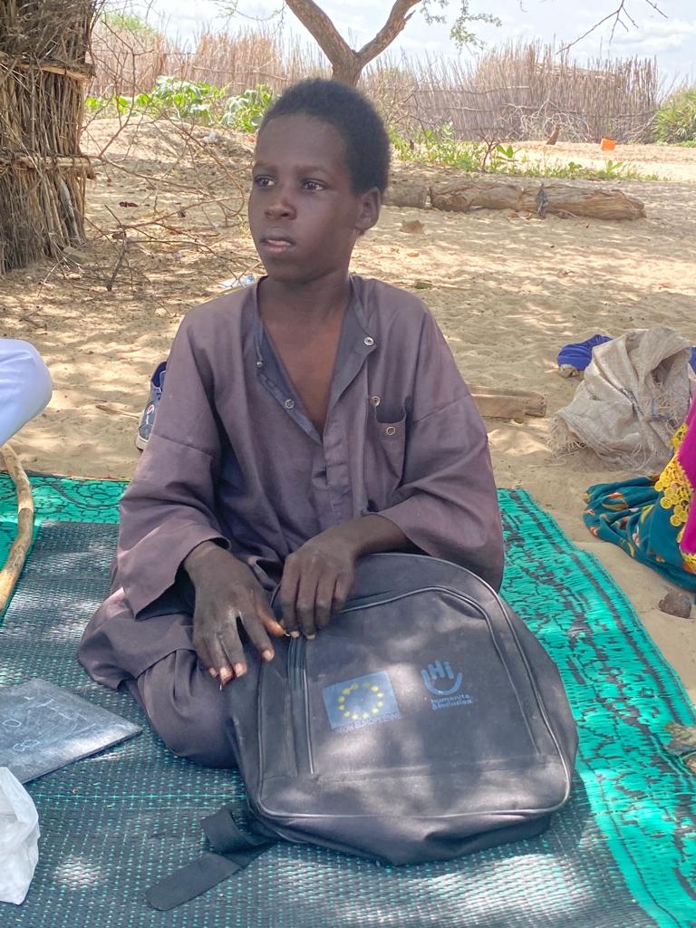 Mahamat est assis avec son sac à dos de fournitures scolaires.