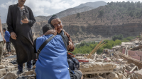 Imi n'Talat, Marokko, 12 september 2023. Een vrouw die enkele familieleden heeft verloren zit op het puin van een vernield gebouw.