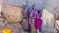 Amina (midden), staat met haar man (links) en een van haar drie kinderen (rechts) voor hun nieuwe huis in een vluchtelingenkamp in Hargeisa. 2022. © HI