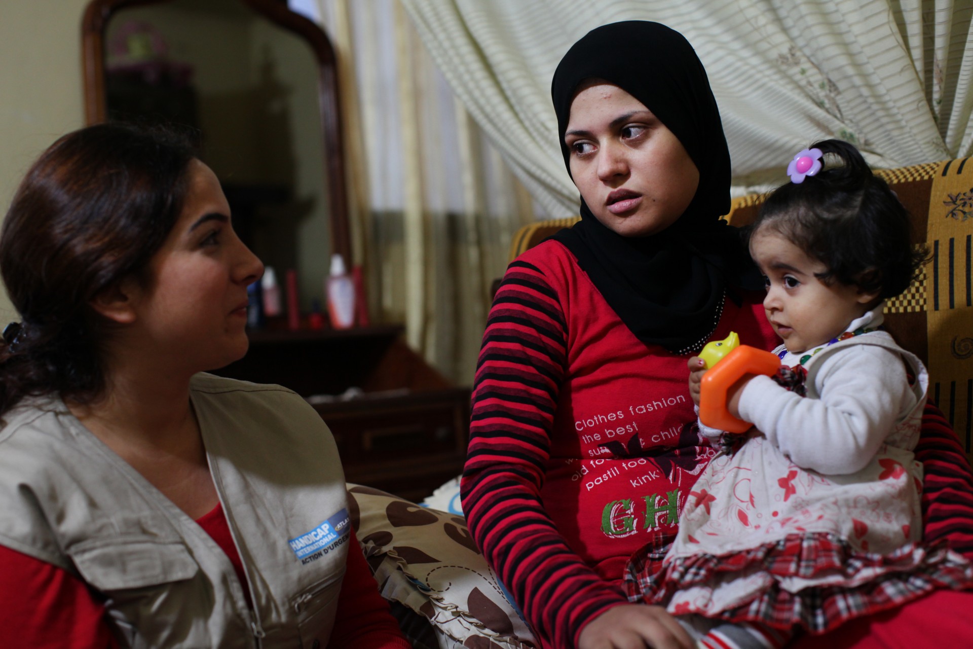 Najah et sa fille, avec la kiné de Handicap International