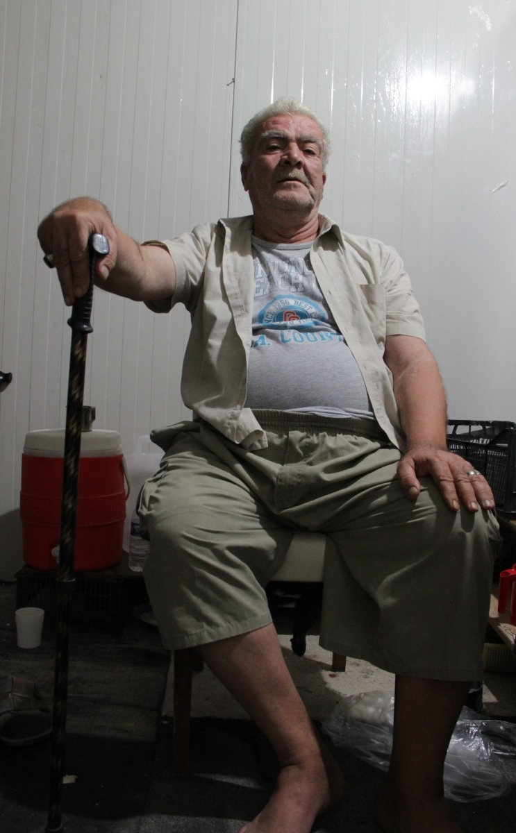 Portret van Sliwa op een stoel, zijn hand rustend op zijn kruk van Handicap International.
