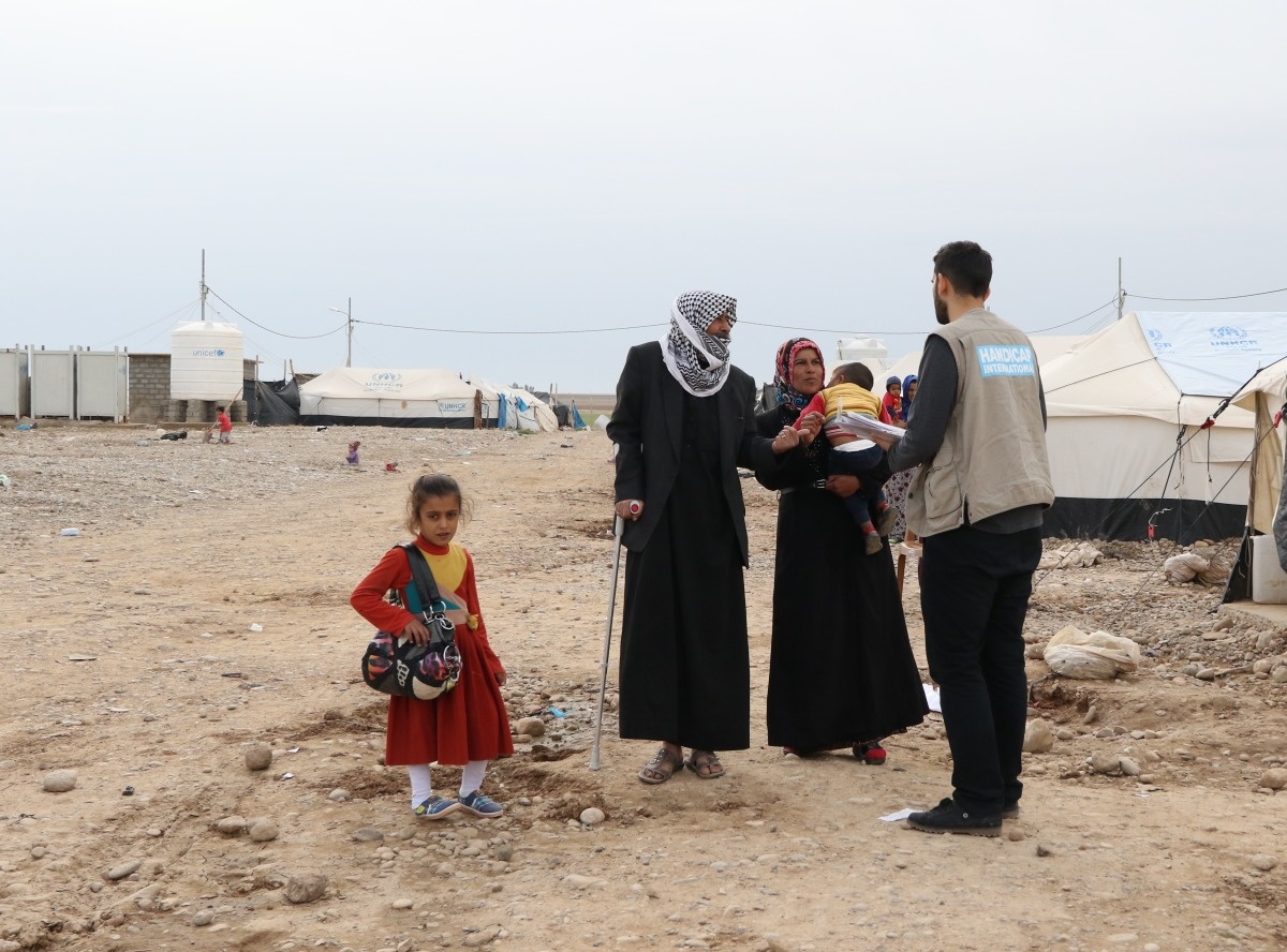 Un collaborateur de Handicap International discute avec une famille de réfugiés à l'intérieur du camp de Laylan