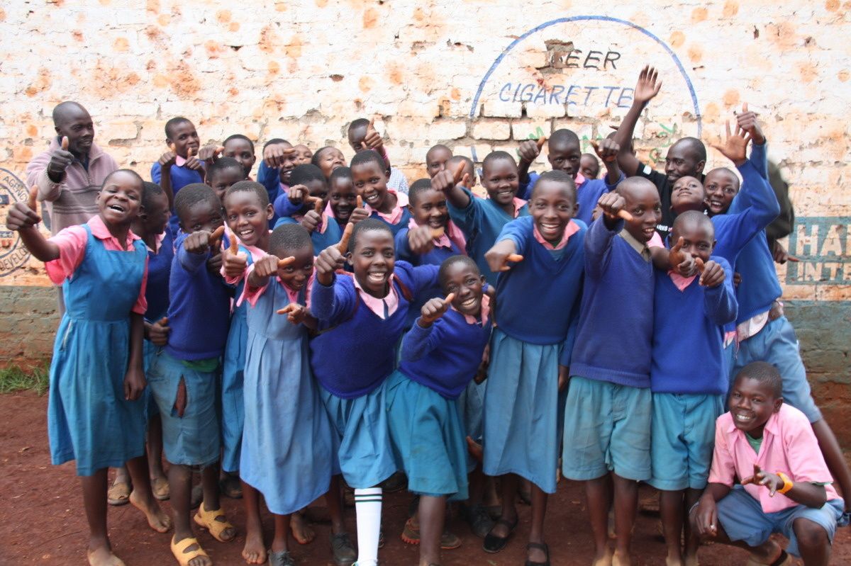 Un groupe d'enfants souriants en uniforme d'écolier dans les tons bleus lève le pouce
